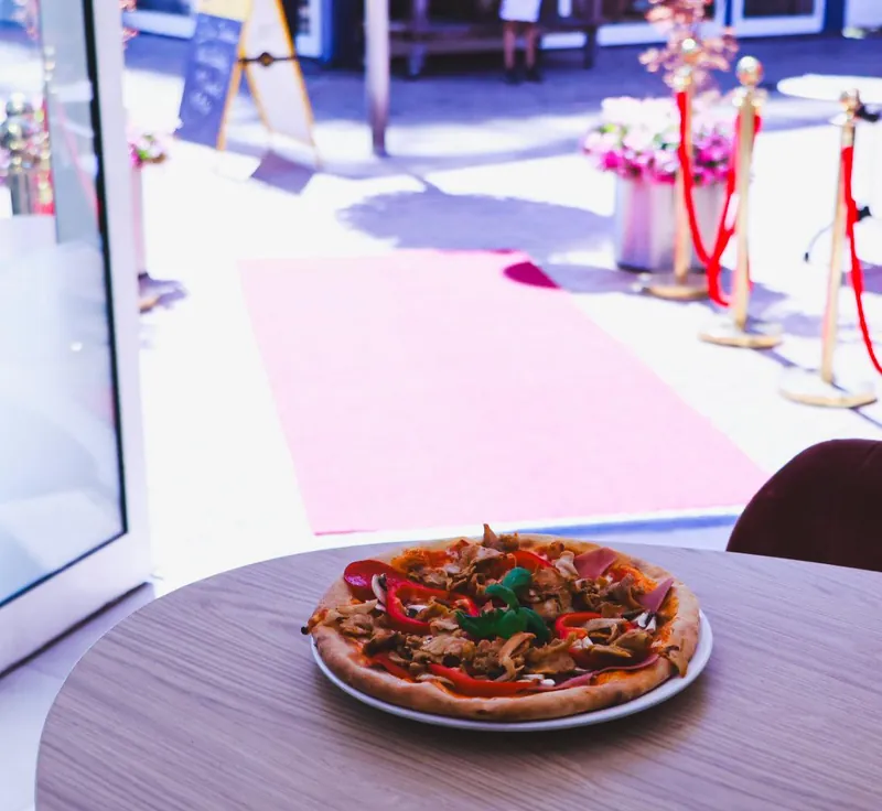 Een pizza op tafel bij het raam, met uitzicht op het plein