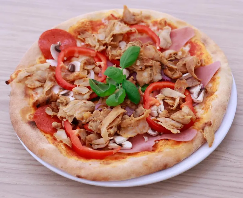 Pizza met kip, tomaat, champignons en verse basilicum