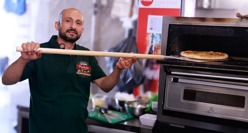 Onze pizzabakker schuift een pizza in de oven